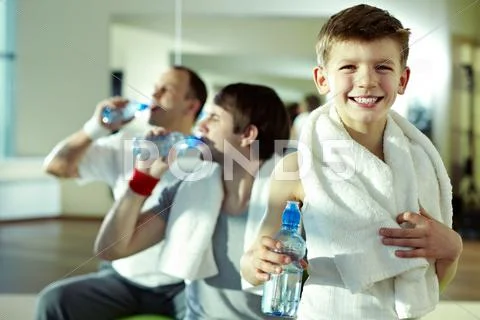 Little boy having break in gym with other men Stock Photos