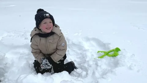 Little boy having fun playing with fresh snow during snowfall.  Stock Footage 232992898