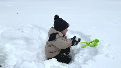 Little boy having fun playing with fresh snow during snowfall.  Stock Footage 232992899