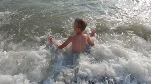 Little boy having fun in waves on the beach Stock Footage 141650182