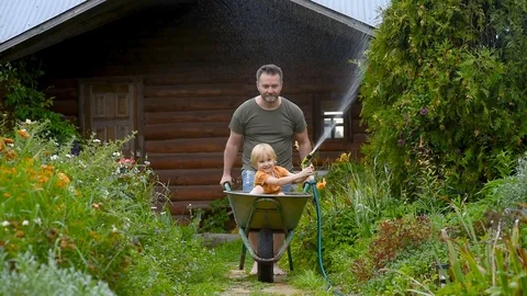 Little boy having fun in a wheelbarrow pushing by dad Stock Footage 124500355