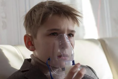 Little boy having inhalation for easing cough. Caucasian blonde boy inhales Stock Photos