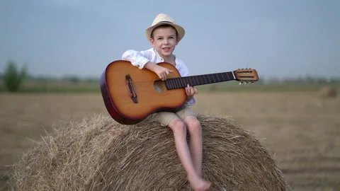 Little boy on a haystack with a guitar Stock Footage 160112627
