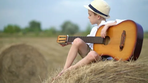 Little boy on a haystack with a guitar Stock Footage 160113238