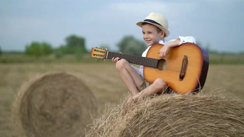Little boy on a haystack with a guitar Stock Footage 160438207