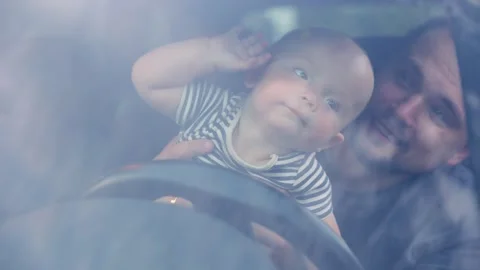 A little boy with his dad inside the car and curiously holding the steering Stock-Footage 309216391