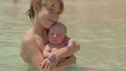 A little boy holds his tiny newborn brother in his hands while sitting in the Stock Footage 303641203