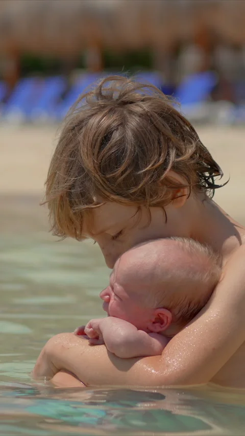 A little boy holds his tiny newborn brother in his hands while sitting in the Stock Footage 310047283