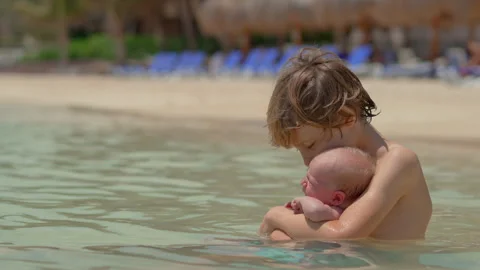 A little boy holds his tiny newborn brother in his hands while sitting in the Stock Footage 310677176