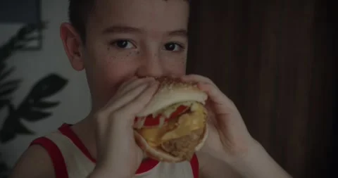 Little boy at home eats burger. Portrait of hungry child Cute little kid eating Stock Footage 315118717