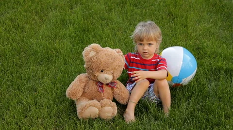 Little boy hugging teddy bear on green grass Stock Footage 58424265