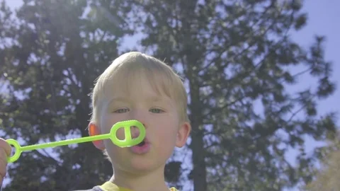 Little boy joyfully blows bubbles Stock Footage 74118278