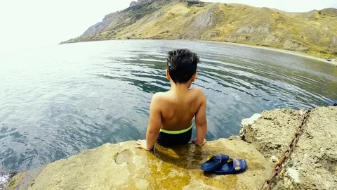 Little boy jumping into the sea from the pier Stock Footage