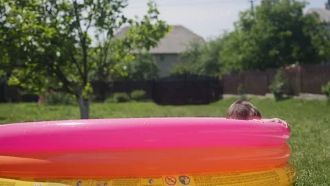 Little boy jumps into inflatable pool with splashes Stock Footage 197060852