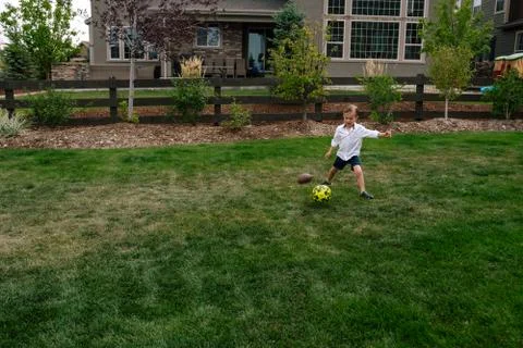 Little boy kicking a soccer ball in the back yard Stock Photos