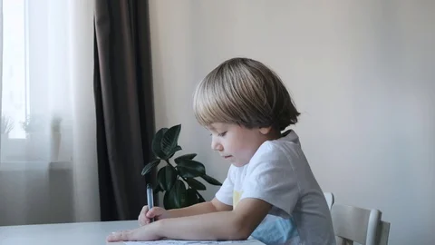 Little boy, kid, sitting at the table at home and drawing, mother kissing and Stock Footage 120434217