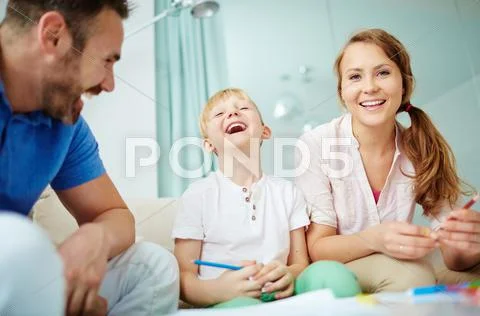 Little boy laughing together with his dad and mom Stock Photos