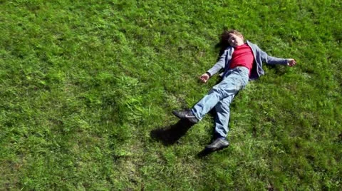 Little boy lay on grass plot and then rolls away Stock Footage 10807902