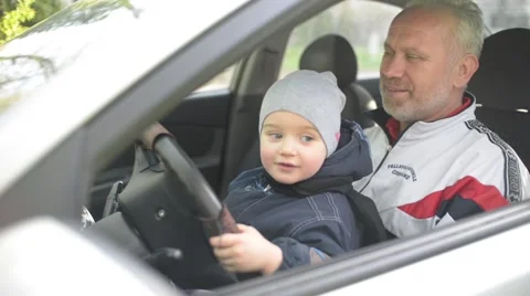 Little boy is learning to drive - steering wheel turns Stock Footage 62303723