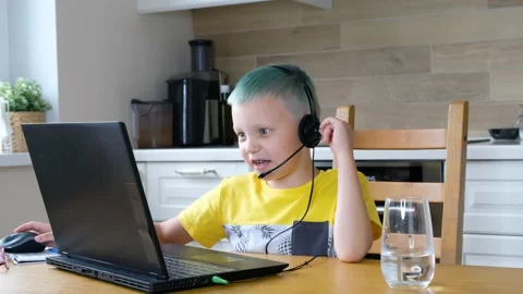 Little boy learning online, sitting in the kitchen with computer and wearing Stock Footage 135719922