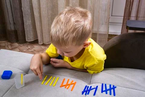 Little boy learns to count with counting sticks Stock Photos