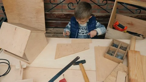 Little boy learns to hammer nails into a wooden plank Stock Footage 119253154