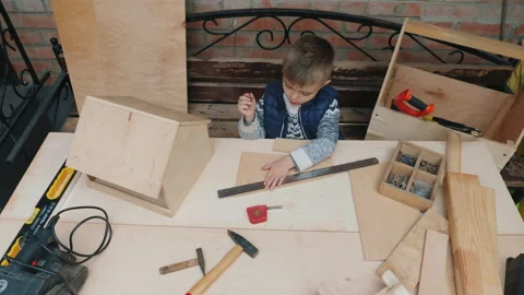 Little boy learns to hammer nails into a wooden plank Stock Footage 280560078