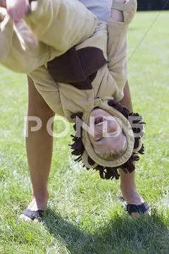 A little boy in a lion costume being held upside down by an adult Stock Photos