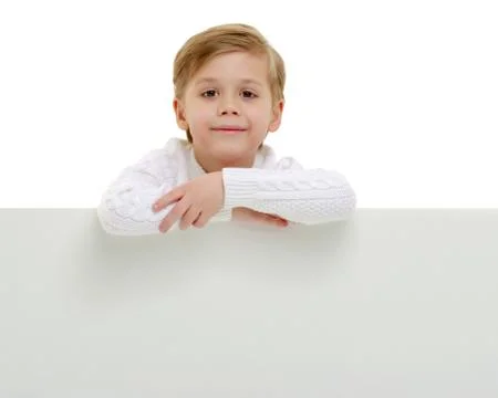 A little boy is looking from behind an empty banner. Stock Photos