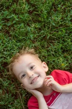 Little boy looking at camera lying on green grass Stock Photos