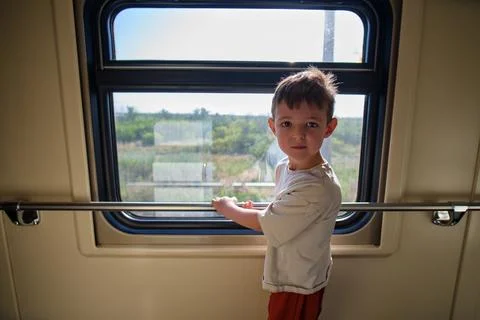 Little boy looking through train window during travel. Child standing in rail Stock Photos