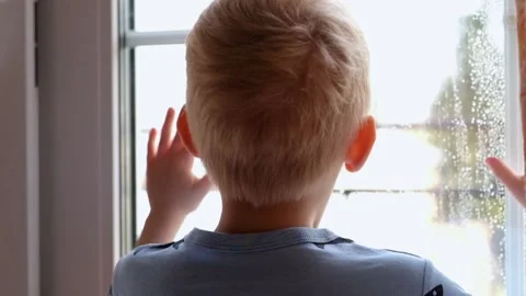 Little boy looking at the window covered with drops of rain Vídeos de archivo 89467069