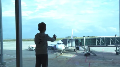 Little boy looking to window waiting airplane in departure lounge in airport Stock Footage 104491334