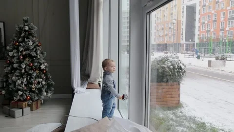 A little boy looks out the window on a Christmas morning in Russia Stock Footage 166040787