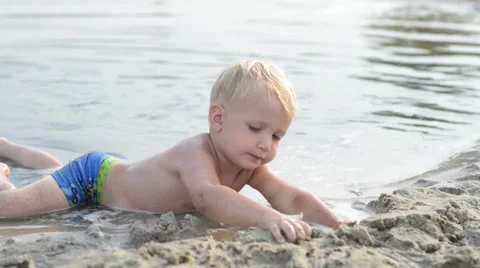 Little boy lying and playing with the mud in the rainy puddle. 스톡 동영상 42190470