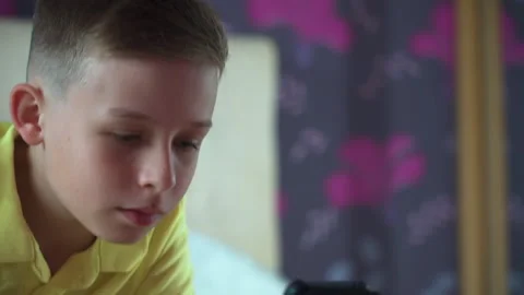 A little boy is lying on the bed. He looks at the phone, smacks. close-up. Stock Footage 132035603