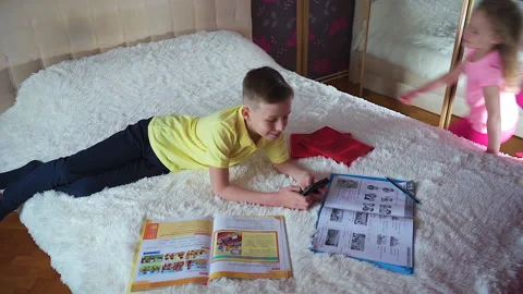 A little boy is lying on the bed. He looks at the phone, smiling. Video stock 132035954
