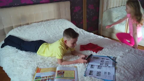 A little boy is lying on the bed. He looks at the phone, smiling. Stock Footage 132036029