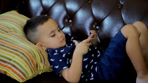 Little boy lying on couch and watching smartphone in hand Stock Footage 91201191