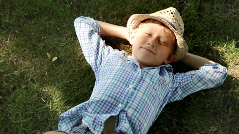 Little boy lying down on ground squinting under flickering sunlight Stock-Footage 131332769