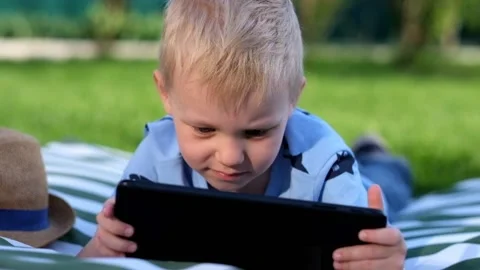 Little boy lying on grass and playing with Tablet, summer outdoors Stock-Footage 89518015