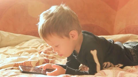 Little boy lying on the sofa playing on the phone close-up Stock Footage 268628814