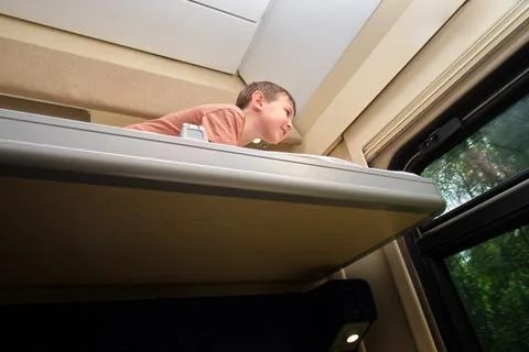 Little boy lying on upper bunk in train compartment looking out of window. Ch Stock Photos