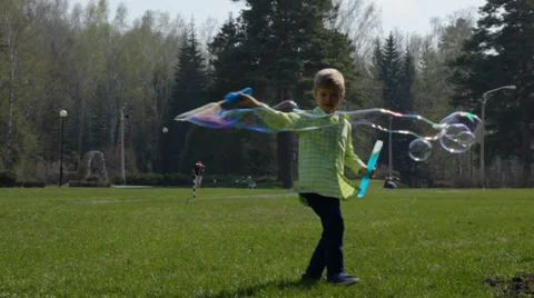 Little boy is making big bubbles in the park Stock Footage 37853122