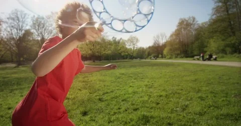 Little Boy is making big bubbles while running . Stock Footage 78164409