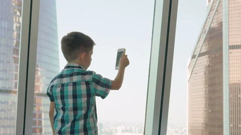 Little boy with mobile phone in the background with skyscrapers. Modern children Stock Footage 93588834