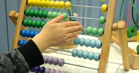 Little boy moves adding numbers using abacus in kindergarten classroom closeup Stock Photos