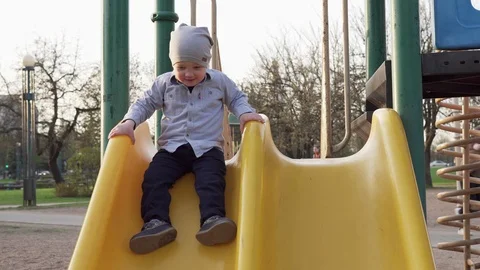 Little boy moving down from children's slide on playground Stock Footage 88973041