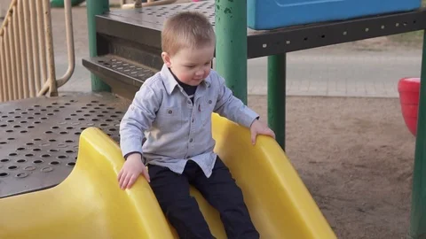 Little boy moving down from children's slide on playground Video stock 88973449