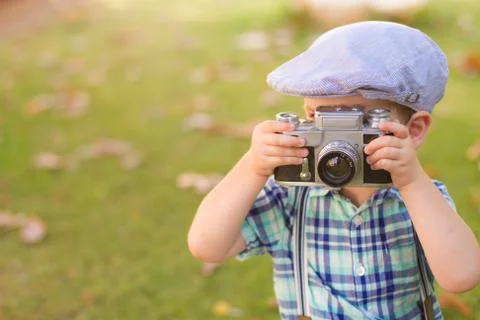 Little boy with an old camera shooting outdoor. using a vintage retro film cam Stock Photos